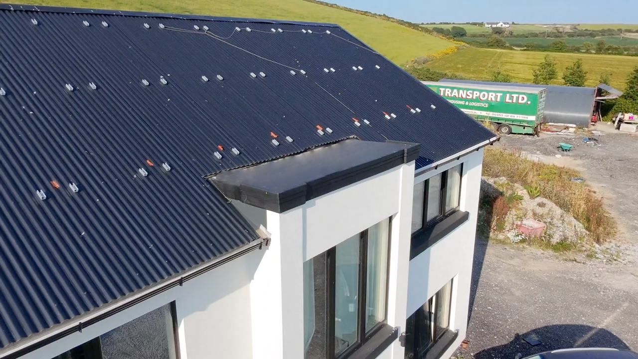 Close-up side view of dark corrugated lightweight roof panels and flashing